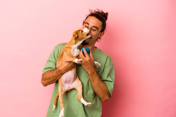 Young caucasian man holding his puppy isolated on pink background - Photo, Image