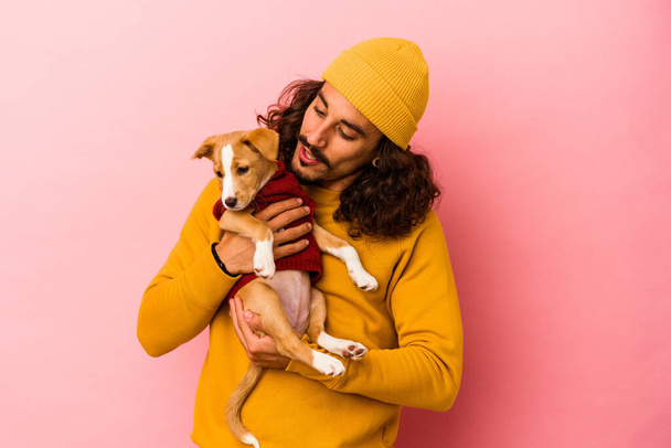 Giovane uomo caucasico tenendo il suo cucciolo isolato su sfondo rosa - Foto, immagini