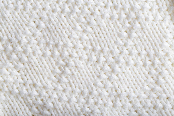 Cómodo suéter de punto cálido hecho de hilos blancos, fondo. Macro, hecho a mano - Foto, Imagen