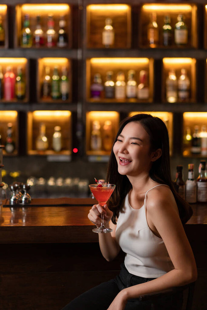 Noční život koncept v nočním klubu hezká žena s růžovým nápojem v ruce vypadá velmi šťastně snad vzhledem k atmosféře. - Fotografie, Obrázek