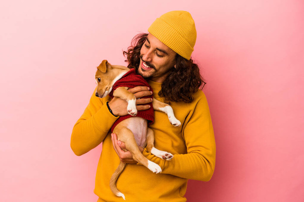 Giovane uomo caucasico tenendo il suo cucciolo isolato su sfondo rosa - Foto, immagini