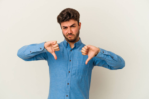 Young caucasian man isolated on white background showing thumb down, disappointment concept. - 写真・画像