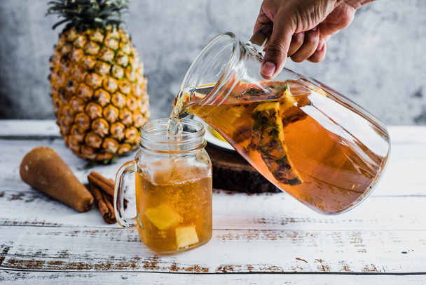 Tepache mexican Fermented pineapple drink and hand holding a Jar with kombucha homemade probiotic superfood sliced pineapple beverage in Mexico city - Foto, imagen