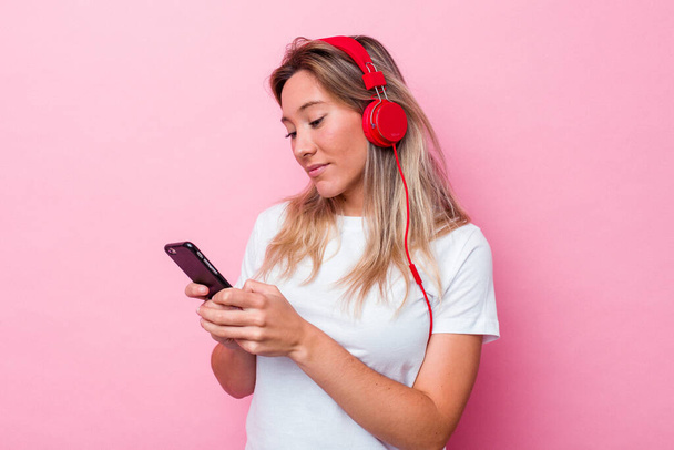 Giovane donna australiana che ascolta musica isolata su sfondo rosa - Foto, immagini