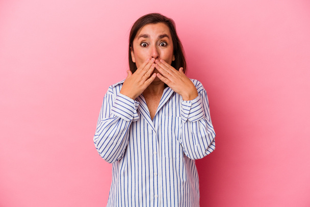 Kaukasische Frau mittleren Alters isoliert auf rosa Hintergrund schockiert Mund mit Händen bedecken. - Foto, Bild