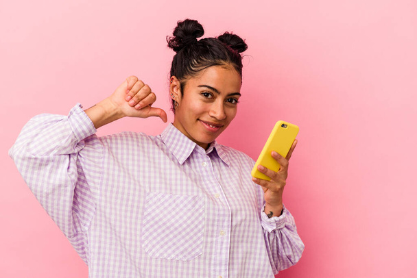 Mladá latinská žena držící mobilní telefon izolovaný na růžovém pozadí cítí hrdost a sebevědomí, příklad následovat. - Fotografie, Obrázek