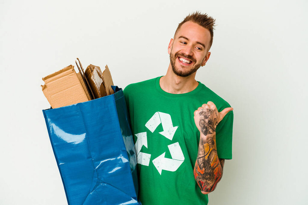 Jovem caucasiano tatuado homem reciclado papelão isolado em pontos de fundo branco com o dedo polegar de distância, rindo e despreocupado. - Foto, Imagem