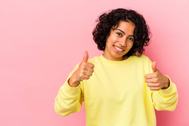 Young curly latin woman isolated on pink background smiling and raising thumb up - Fotoğraf, Görsel