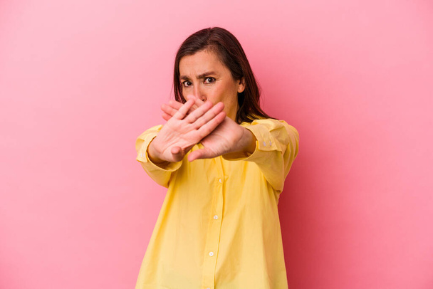 Middelbare leeftijd blanke vrouw geïsoleerd op roze achtergrond staan met uitgestrekte hand tonen stopteken, voorkomen dat u. - Foto, afbeelding