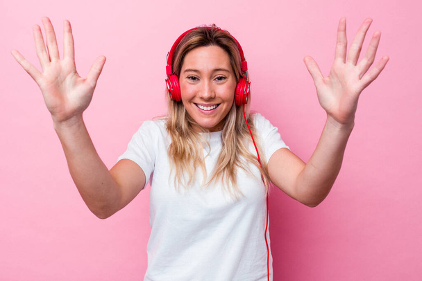 Young australian woman listening music isolated on pink background receiving a pleasant surprise, excited and raising hands. - Foto, Imagem