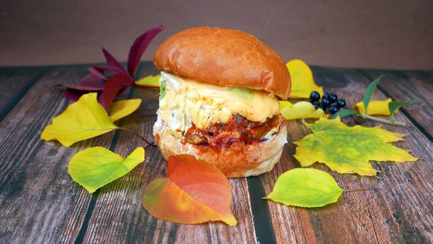 burger és sült krumpli fa alapon őszi levelek, gyorsétterem koncepció, elvenni élelmiszer koncepció, szezon értékesítési koncepció - Fotó, kép