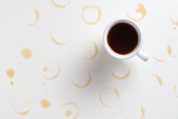Cup of coffee with stains on white table, view from above - Foto, imagen