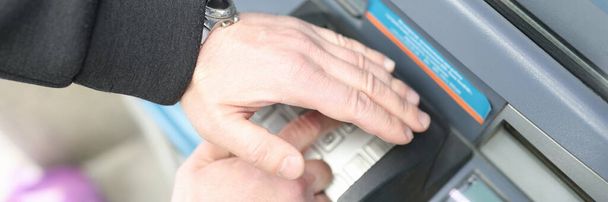 Adam ATM klavyesinden şifreyi giriyor ve eliyle kapatıyor. - Fotoğraf, Görsel