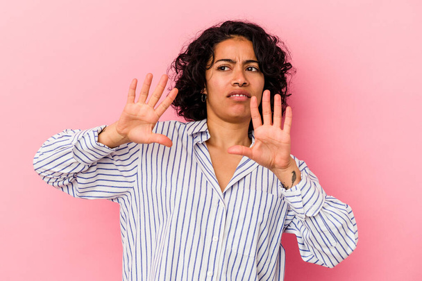 Young curly latin woman isolated on pink background rejecting someone showing a gesture of disgust. - Photo, Image