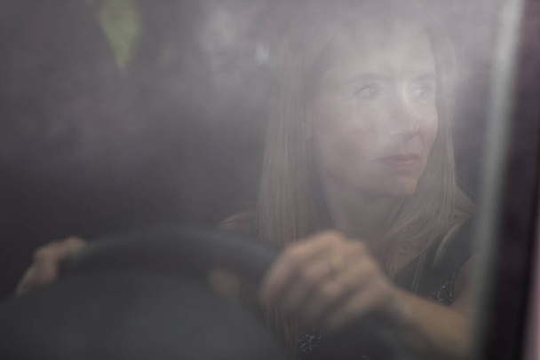 Pretty midle aged woman at the steering wheel of her car commuting to work - Фото, зображення