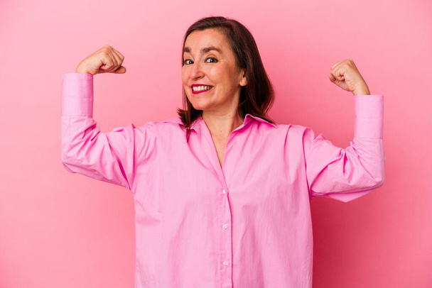Middle age caucasian woman isolated on pink background showing strength gesture with arms, symbol of feminine power - Photo, Image