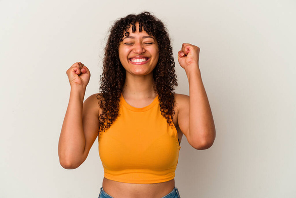 Young mixed race woman isolated on white background celebrating a victory, passion and enthusiasm, happy expression. - Foto, Imagen