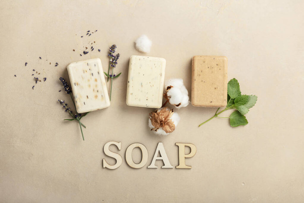 Natural soap bars - lavender, cotton, patchouli - ingredients and wooden letters on natural stone background, flat lay - Фото, изображение