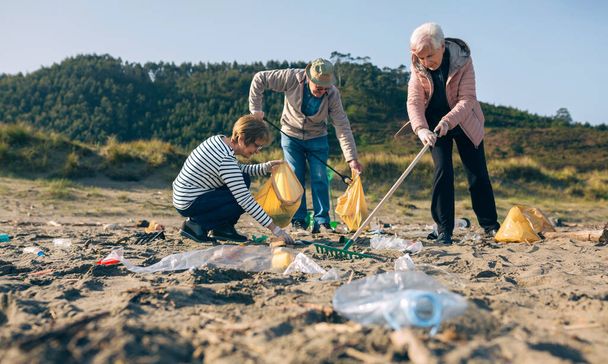 Ανώτεροι εθελοντές καθαρίζουν την παραλία - Φωτογραφία, εικόνα