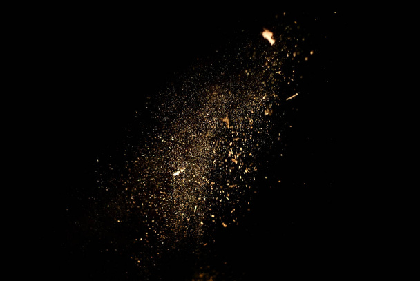 Dust and wood chips on a black background. Dirt particles fly in the air. Layout for design. Some dust particles are blurred to transmit the effect of motion. - Фото, зображення