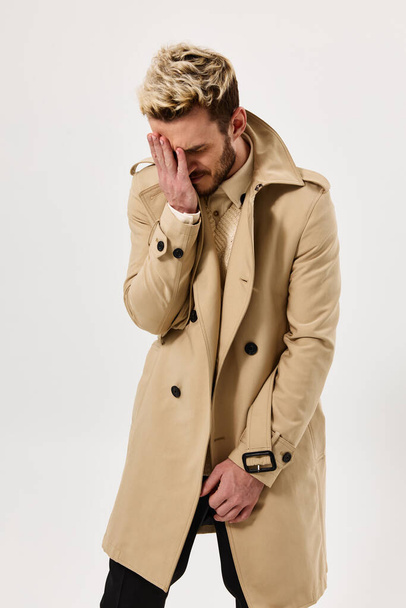 férfi bézs kabátban fogja kéz a kézben arc érzelmek stúdió - Fotó, kép