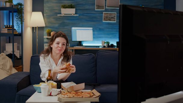 Persona comiendo deliciosa hamburguesa y papas fritas en la sala de estar - Foto, imagen
