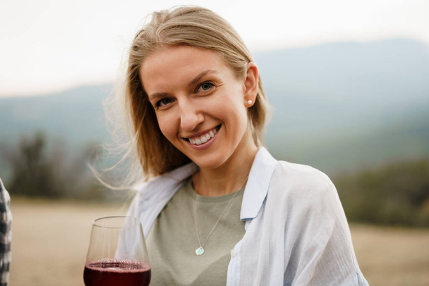 Beautiful young female with a glass of red wine in mountains - Φωτογραφία, εικόνα