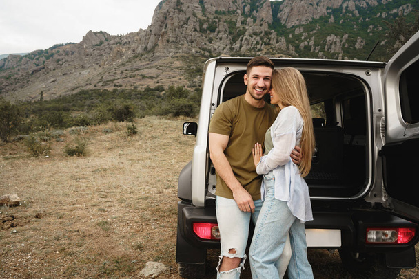Young happy couple on a road trip sitting in car trunk - Φωτογραφία, εικόνα