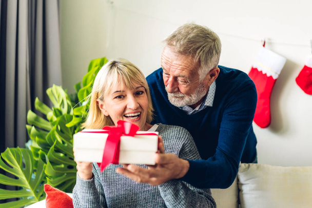 Romantický sladký starší pár baví a usmívá se při oslavě těší Valentýna den spolu. Senior muž dává dárek box překvapení pro manželku v Valentýna doma - Fotografie, Obrázek