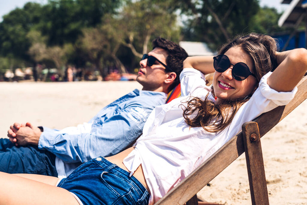 Διακοπές ρομαντικοί εραστές νεαρό ευτυχισμένο ζευγάρι αγκαλιά και να καθίσει στην άμμο και ατενίζοντας τη θάλασσα διασκεδάζοντας και χαλαρώνοντας μαζί με αντίγραφο banner χώρο για την προσθήκη κειμένου για τροπική παραλία. - Φωτογραφία, εικόνα