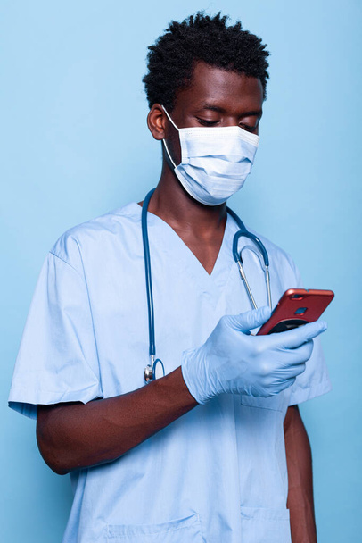 Hombre trabajando como enfermero mirando el teléfono inteligente en la mano - Foto, Imagen