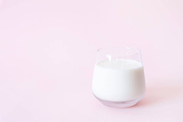 ピンクの背景のガラスの中に新鮮な牛乳 - 写真・画像