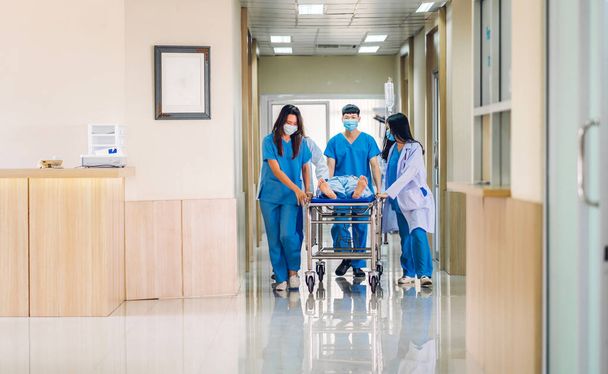 Група професійних лікарів-команди та асистент зі стетоскопом в уніформі приймають серйозно пораненого пацієнта до експлуатації кімнати екстреної медичної допомоги в лікарні.
 - Фото, зображення