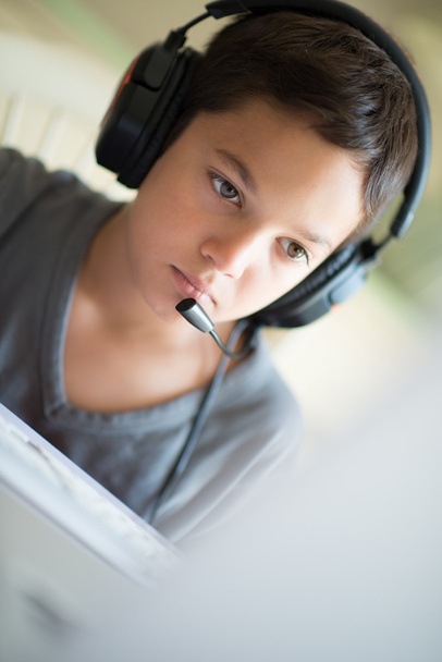 Child playing on the computer with headphones - Valokuva, kuva