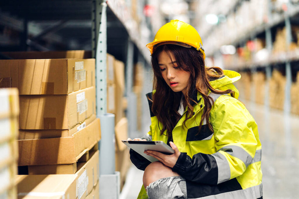 Portrait of smiling asian engineer in helmet woman use tablet computer order details and checking goods and supplies on shelves with goods background in warehouse.logistic and business export - Foto, imagen