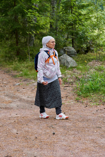 Uskonnolliseksi pyhiinvaeltajaksi pukeutunut nainen kävelee metsätietä pitkin. Pyhiinvaeltajan muotokuva metsätiellä - Valokuva, kuva