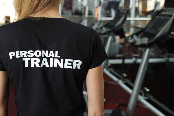 Personal trainer in modern gym, back view - Фото, изображение