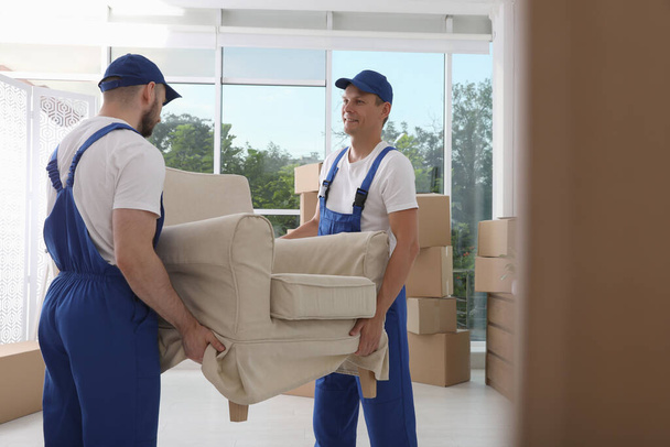 Moving service employees carrying armchair in room - Foto, immagini