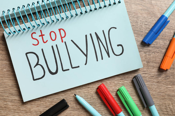 Text Stop Bullying written in notebook and markers on wooden table, flat lay - Zdjęcie, obraz