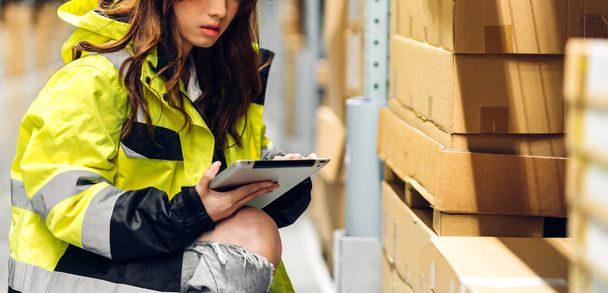 Portrait of smiling asian engineer in helmet woman use tablet computer order details and checking goods and supplies on shelves with goods background in warehouse.logistic and business export - Фото, изображение