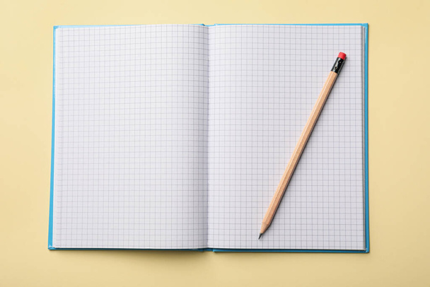 Open notebook with blank sheets and pencil on beige background, top view - Foto, Bild