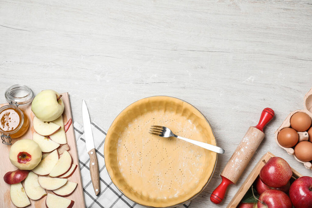 Flat lay composition with raw dough, fork and ingredients on white wooden table, space for text. Baking apple pie - Foto, Imagem