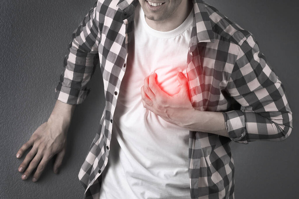 Man having heart attack on dark background, closeup view - Фото, изображение