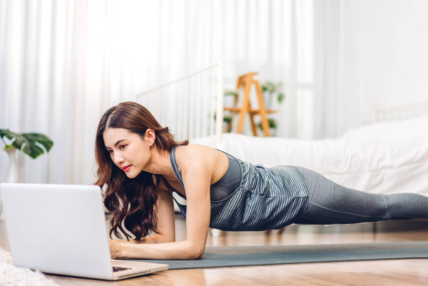Portrait sport asiatique beauté corps mince femme en vêtements de sport assis se détendre et fille pratiquer le yoga et faire des exercices de remise en forme avec ordinateur portable dans la chambre à coucher à la maison. - Photo, image
