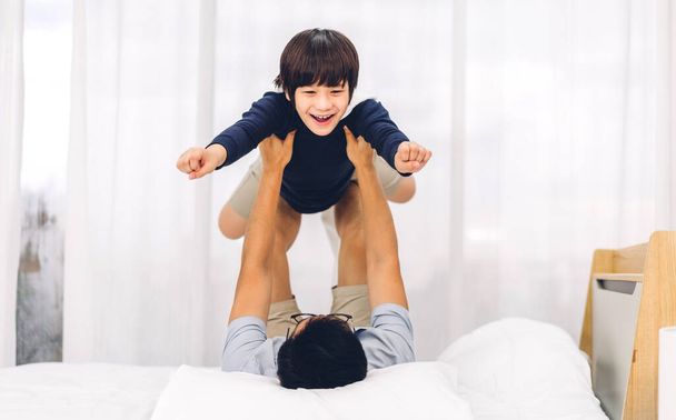 Portré a boldog szerelem ázsiai család apa hordozza kis ázsiai fiú mosolygós játszik szuperhős és szórakozás pillanatok jó idő az ágyban otthon - Fotó, kép