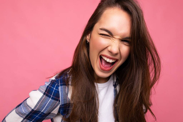 Young beautiful brunet woman. Trendy lady in casual summer hipster shirt . Positive female shows facial sincere emotions. Funny model isolated on pink background with free space - Φωτογραφία, εικόνα