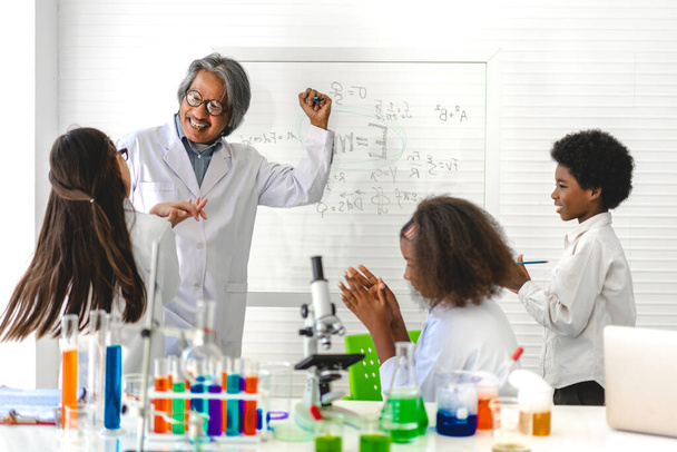 Ομάδα εφήβων μαθητών μαθαίνουν με το δάσκαλο και να κάνει ένα χημικό πείραμα και κρατώντας δοκιμαστικό σωλήνα στα χέρια στην εργαστηριακή τάξη πειράματος στο τραπέζι στο σχολείο. - Φωτογραφία, εικόνα