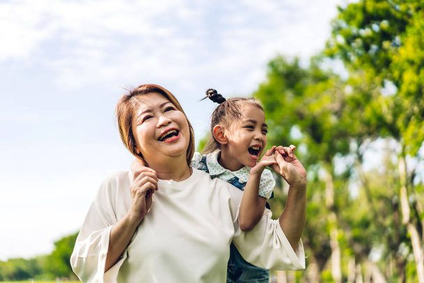 Портрет щасливої любові азіатської бабусі і маленької азіатської милої дівчинки насолоджуйтесь відпочинком у літньому парку. Молода дівчина зі своїм смішним бабусею і бабусею посміхається разом. Сім'я і єдність
 - Фото, зображення