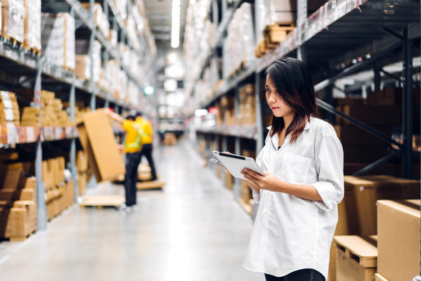 Portrait of asian woman standing and order details on tablet for checking goods and supplies on shelves store at factory with goods background in distribution industry warehouse.logistic and business export - Фото, зображення