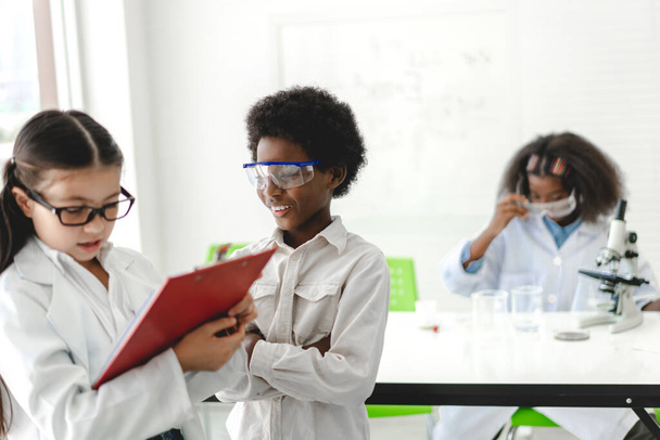 Groep van tiener schattige kleine student kind leren onderzoek en het doen van een chemisch experiment, terwijl het maken van het analyseren en mengen van vloeistof in reageerbuis op experiment laboratoriumles op school.Onderwijs - Foto, afbeelding